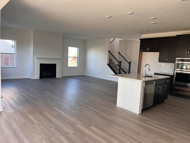 kitchen featuring backsplash, a kitchen island with sink, sink, hardwood / wood-style flooring, and appliances with stainless steel finishes