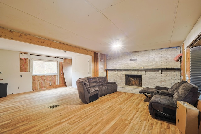 living room featuring a fireplace, light hardwood / wood-style floors, and brick wall