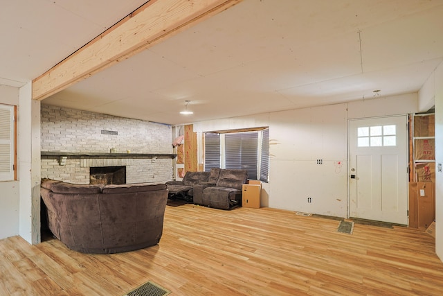 living room with hardwood / wood-style floors, a fireplace, and brick wall