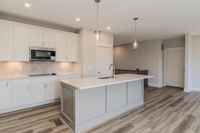 kitchen with sink, a center island with sink, and white cabinets