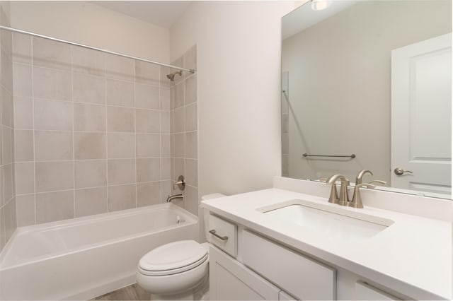 full bathroom featuring vanity, tiled shower / bath, and toilet