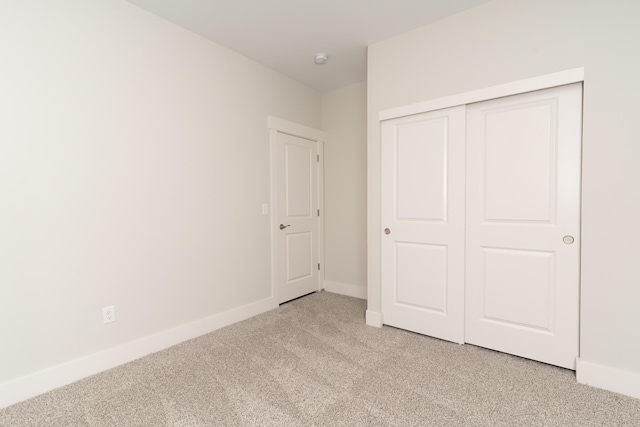 unfurnished bedroom with light colored carpet and a closet