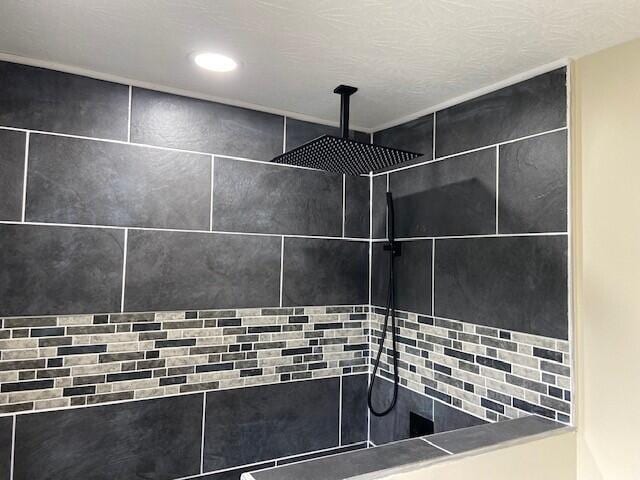 interior details featuring a textured ceiling and tiled shower