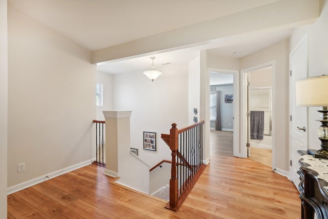 corridor featuring light wood finished floors, an upstairs landing, and baseboards