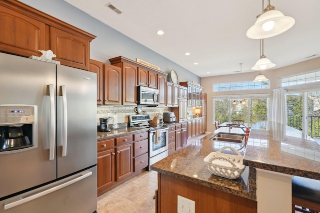 kitchen with tasteful backsplash, visible vents, appliances with stainless steel finishes, a sink, and dark stone countertops