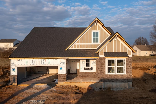 view of front of house featuring a garage, brick siding, and a shingled roof