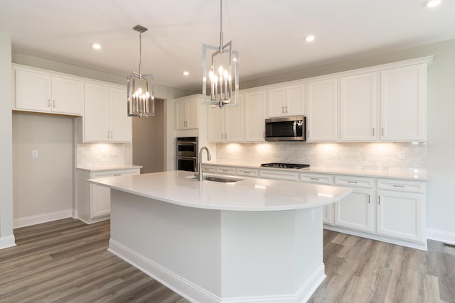 kitchen featuring stainless steel appliances, a sink, light wood-style flooring, white cabinets, and recessed lighting