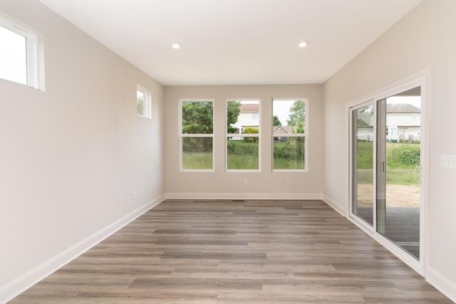 spare room featuring plenty of natural light, baseboards, recessed lighting, and wood finished floors
