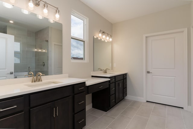 full bathroom with a tile shower, tile patterned floors, two vanities, and baseboards