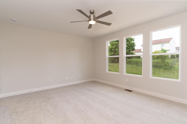 spare room with baseboards, light colored carpet, and a ceiling fan