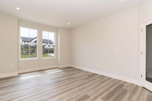 empty room with light wood finished floors, recessed lighting, and baseboards