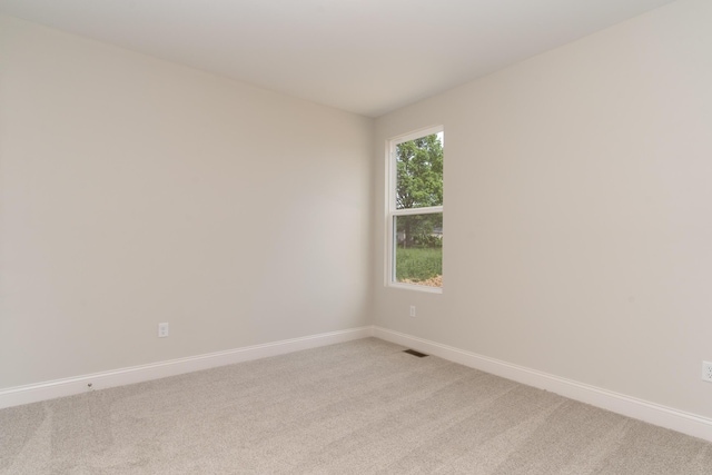 unfurnished room with light colored carpet and baseboards