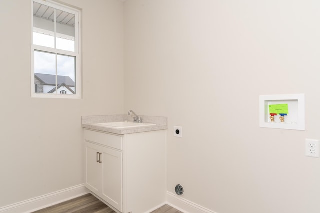clothes washing area featuring hookup for an electric dryer, a sink, wood finished floors, and baseboards