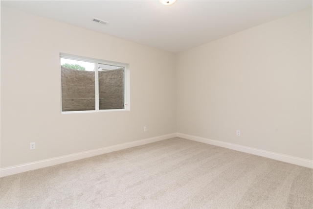 spare room featuring light carpet and baseboards