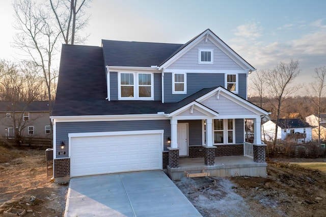 view of front of home featuring a porch, concrete driveway, brick siding, and a garage