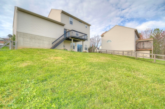 rear view of house with fence, a deck, and a lawn