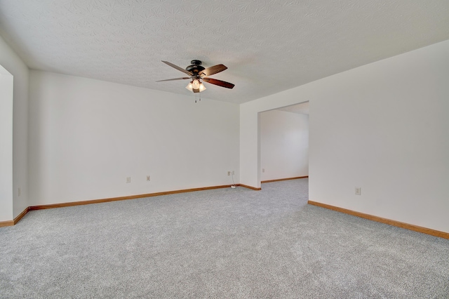 empty room with a ceiling fan, carpet, a textured ceiling, and baseboards