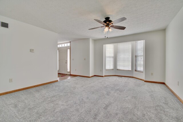 empty room featuring carpet, visible vents, ceiling fan, and baseboards