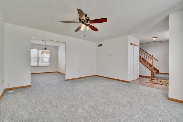 empty room featuring carpet, visible vents, stairway, and baseboards