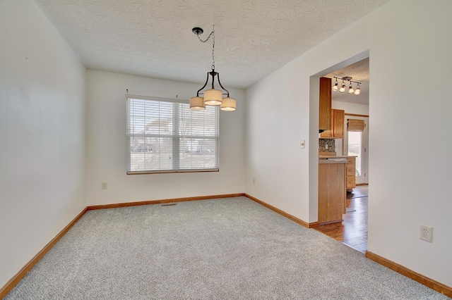 unfurnished room with carpet, a textured ceiling, and baseboards