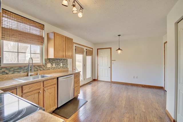 kitchen featuring a sink, light wood-style floors, light countertops, stainless steel dishwasher, and tasteful backsplash