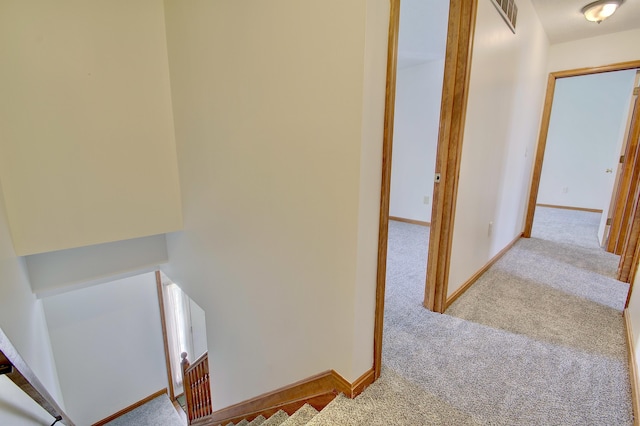 hall with carpet floors, visible vents, and baseboards