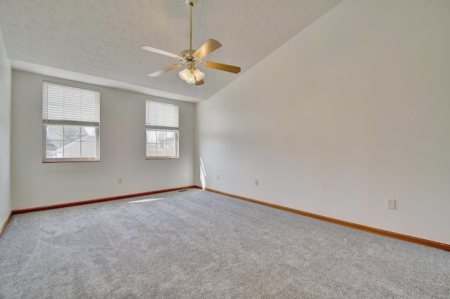 spare room featuring carpet flooring, vaulted ceiling, a textured ceiling, and baseboards