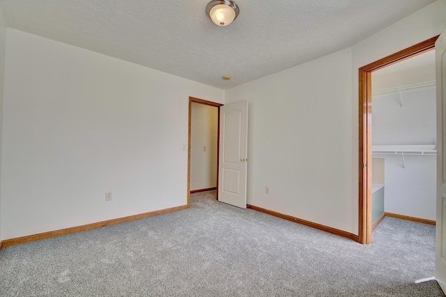 unfurnished bedroom featuring a closet, carpet flooring, a textured ceiling, and baseboards