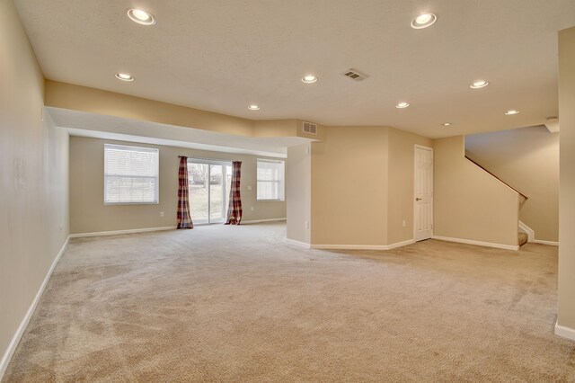 interior space with stairs, light carpet, visible vents, and baseboards