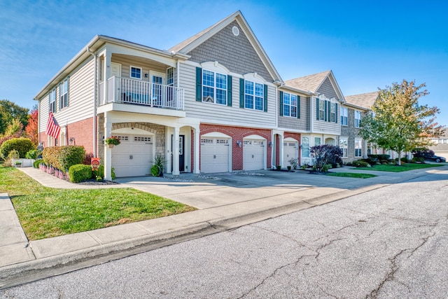 multi unit property featuring a balcony, a garage, brick siding, driveway, and a front yard