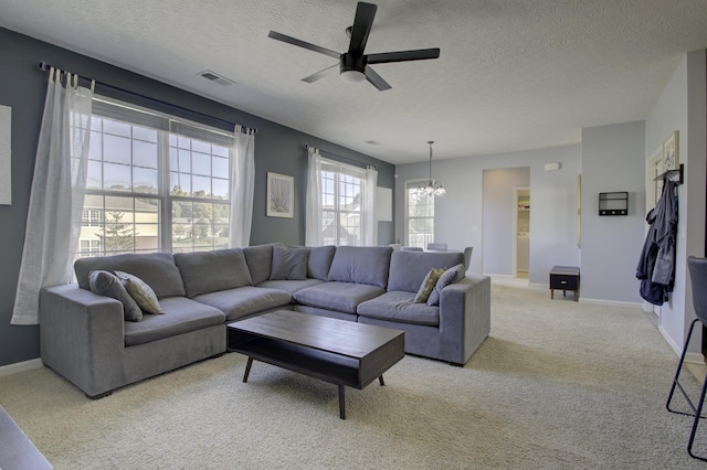 living area featuring carpet floors, baseboards, visible vents, and ceiling fan with notable chandelier