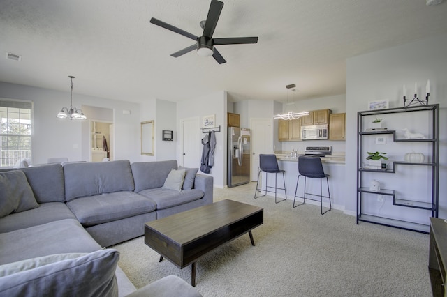 living area featuring ceiling fan with notable chandelier, visible vents, and light colored carpet