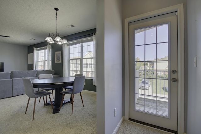 dining room with a textured ceiling, a chandelier, carpet floors, visible vents, and baseboards