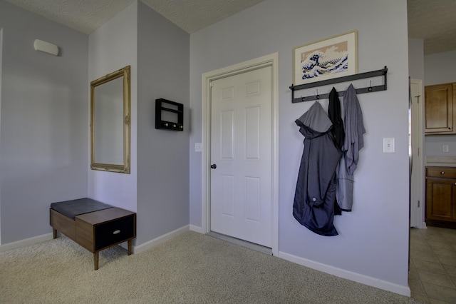 interior space featuring carpet, tile patterned flooring, a textured ceiling, and baseboards