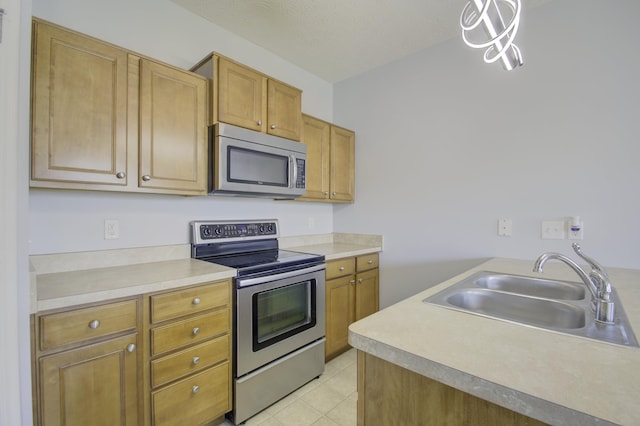 kitchen featuring a textured ceiling, a sink, light countertops, appliances with stainless steel finishes, and brown cabinetry