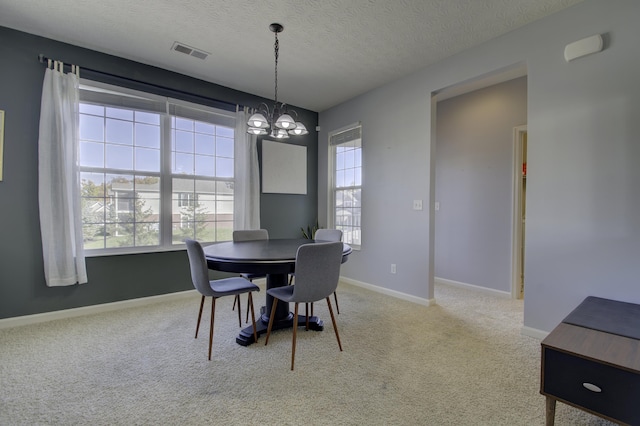 carpeted dining room with visible vents, a notable chandelier, a textured ceiling, and baseboards