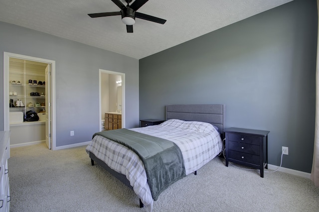 bedroom with a textured ceiling, a spacious closet, carpet flooring, and baseboards