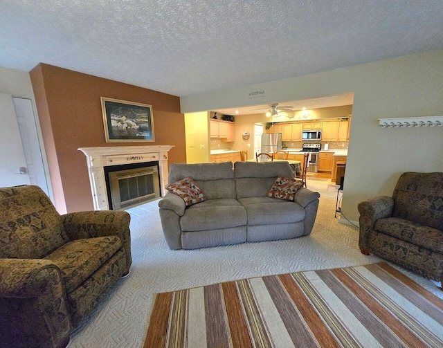 living room featuring light carpet, a textured ceiling, and a glass covered fireplace