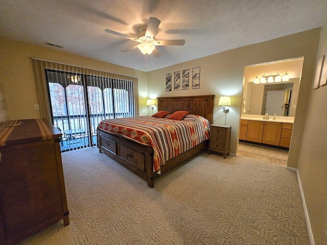 bedroom featuring visible vents, light colored carpet, a textured ceiling, ensuite bath, and access to outside