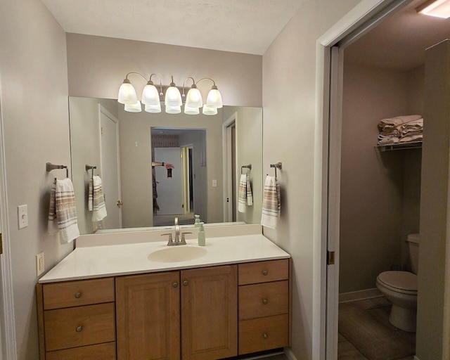 bathroom featuring toilet, baseboards, and vanity