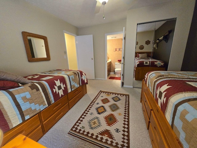 bedroom featuring baseboards, ceiling fan, ensuite bath, and light colored carpet