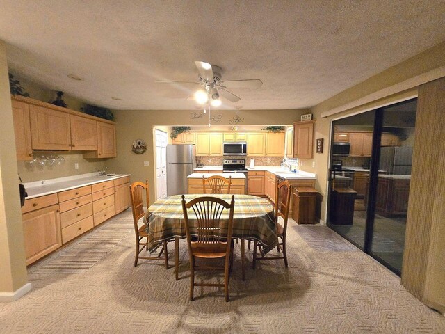 dining room featuring light carpet, ceiling fan, and a textured ceiling