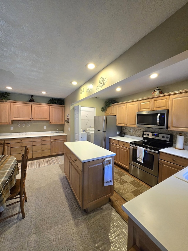 kitchen featuring washer / clothes dryer, backsplash, stainless steel appliances, light countertops, and a sink