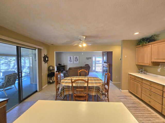 dining area with light carpet, ceiling fan, a textured ceiling, and baseboards