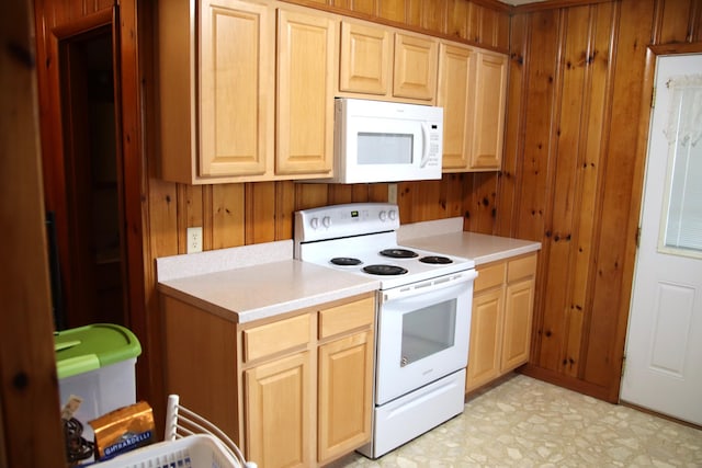 kitchen with wood walls, white appliances, and light brown cabinets