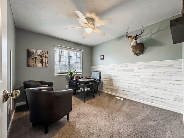 carpeted home office with ceiling fan and a textured ceiling