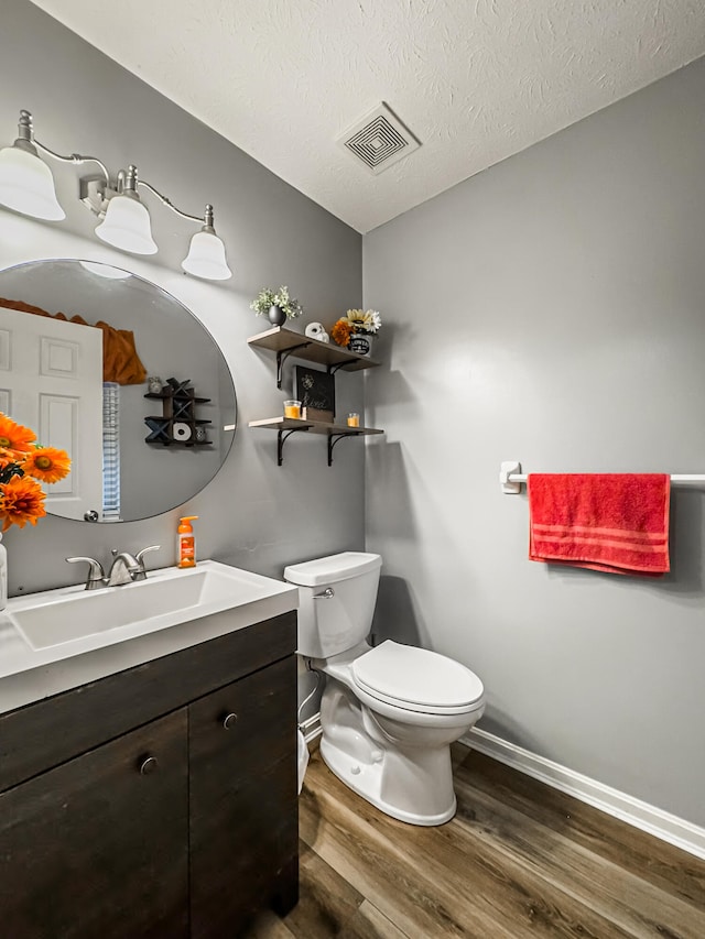 bathroom with a textured ceiling, vanity, hardwood / wood-style flooring, and toilet