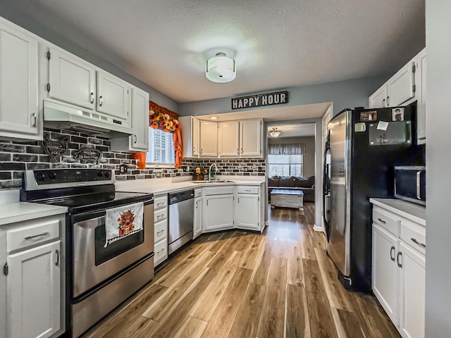 kitchen with a wealth of natural light, white cabinets, stainless steel appliances, and wood-type flooring