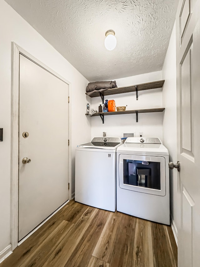 clothes washing area featuring washer and dryer, a textured ceiling, and dark wood-type flooring