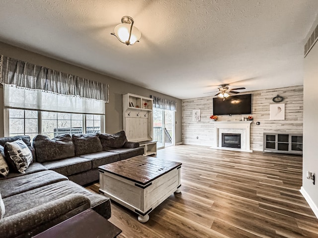 living room featuring hardwood / wood-style floors, ceiling fan, a textured ceiling, and wooden walls